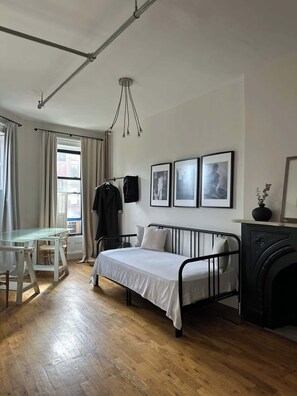 Ein Schlafzimmer mit Bett, Schreibtisch, Stuhl, Heizkörper und einem an der Wand befestigten Fernseher.