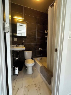 A bathroom with a toilet, sink, and bathtub. - Brooklyn artistic studio apartment! (Brooklyn)
