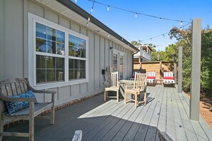Eine Terrasse mit Tisch und Stühlen, eine hölzerne Bank und ein überdachter Bereich mit Liegestühlen.