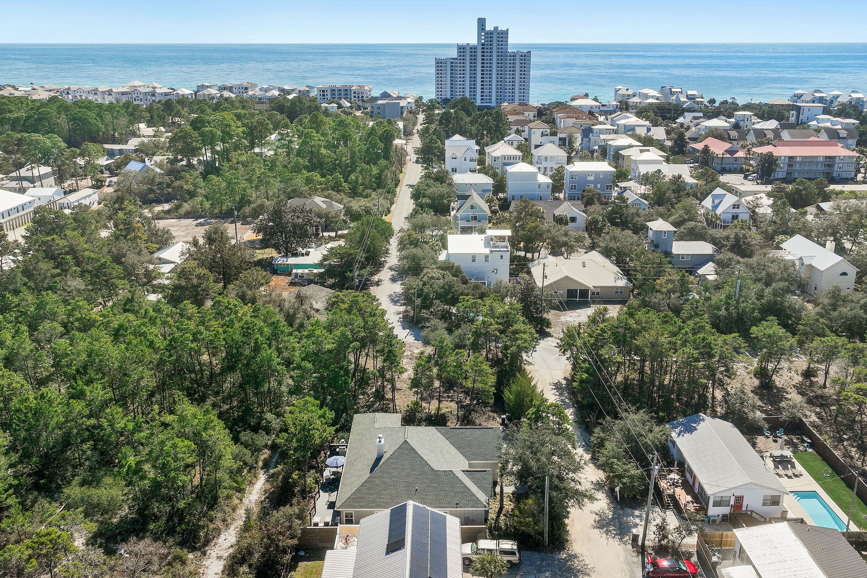 Zona residencial a la costa, amb cases, una platja i un edifici alt al fons.