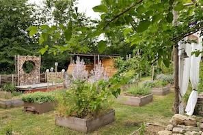 Un jardin avec des plates-bandes surélevées, une arche en bois et une structure en forme de cloche.