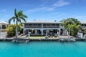 A two-story house with a pool, surrounded by palm trees and a clear blue sky. - Duck Key Waterfront Paradise B Private Balcony (Duck Key)