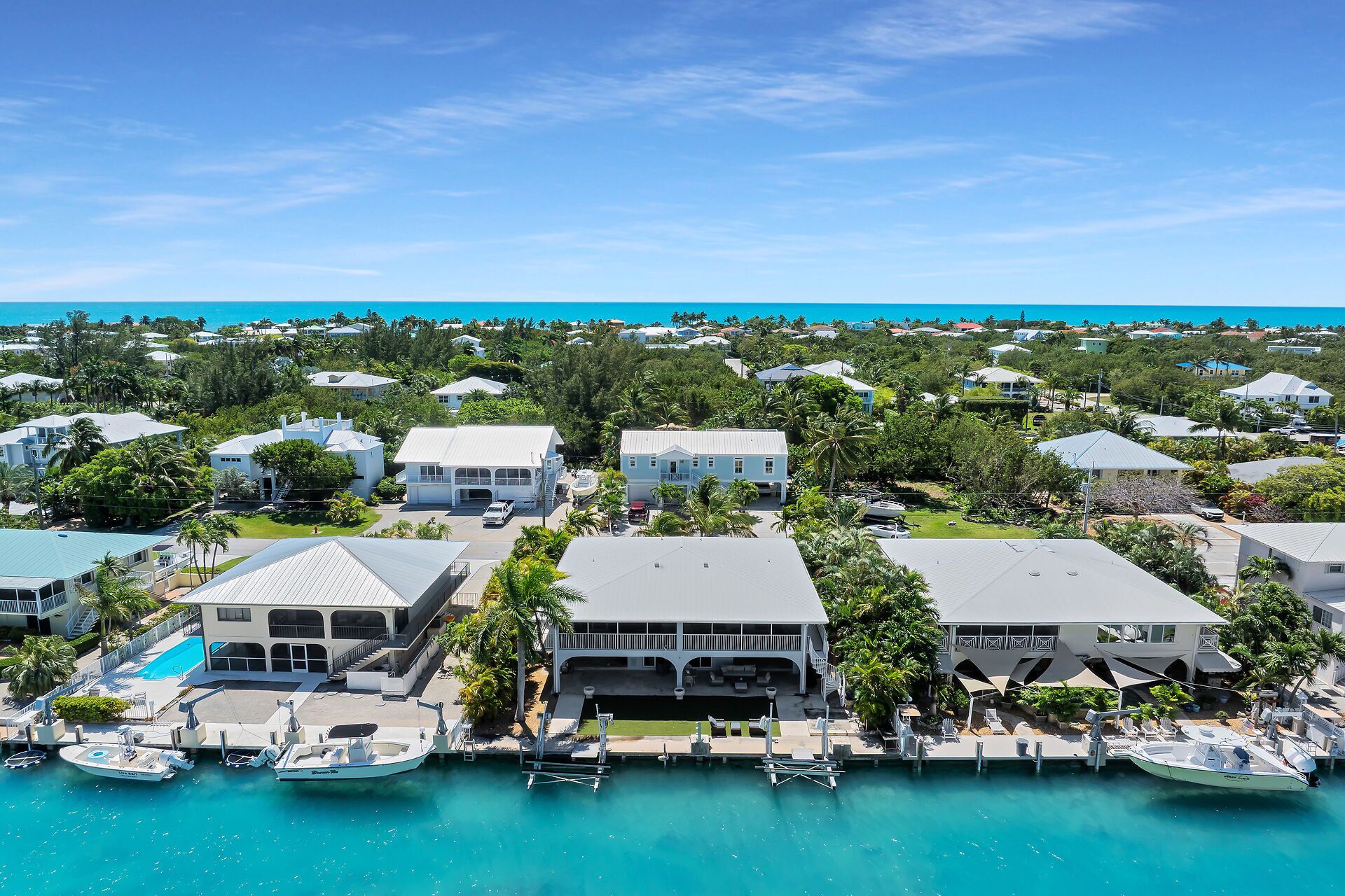 A coastal residential area with houses, a marina, and a clear view of the ocean.