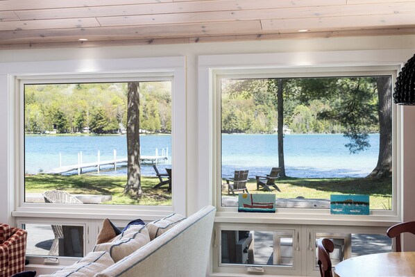 A room with a view of a lake, a sofa, and a table.