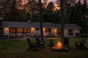 A two-story house with a patio area, outdoor seating, and a fire pit.