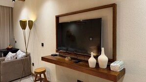 A modern living room with a mounted TV, wooden console, and a small stool. - luxury hotel apartment porto golf marina (Marsa Matrouh Governorate)