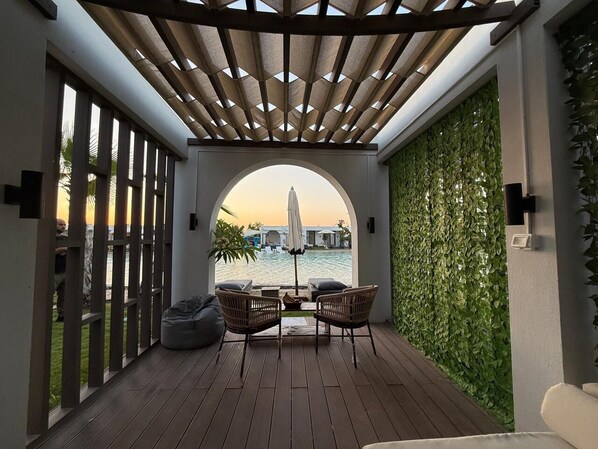 A covered outdoor seating area with a view of a body of water and a building in the distance.