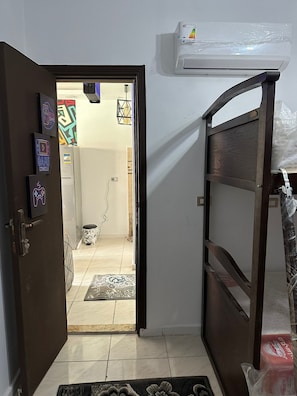 An open doorway leading to a room with a tiled floor, a white wall, and a ceiling-mounted air conditioning unit.