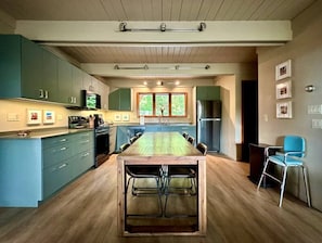 A modern kitchen with a central island, built-in appliances, and a large window. - Goathaus | Iconic A-Frame with Bay Views (Sister Bay)