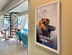 A modern interior with a spiral staircase, a framed poster, and a blue sofa.