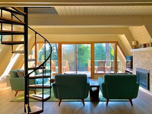 A spacious living area with a spiral staircase, large windows, and a fireplace.