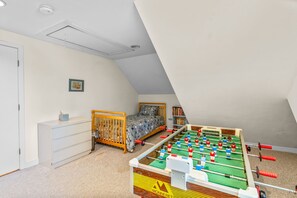 A room with a bed, a dresser, a foosball table, and a bookshelf. - New Rental-Bright Coves, Walk to Marina and Popponesset Spit and clean! (Mashpee)