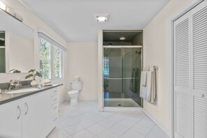 A modern bathroom with a glass-enclosed shower, a toilet, and a sink with a mirror. - New Rental-Bright Coves, Walk to Marina and Popponesset Spit and clean! (Mashpee)
