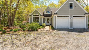 Une maison d’habitation avec allée, garage et jardin aménagé.