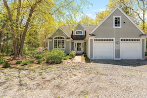 Una casa de dos pisos con entrada de coches, garaje y un jardín ajardinado.