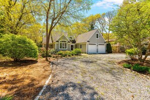 A house with a gravel driveway, a garage, and a well-maintained garden.