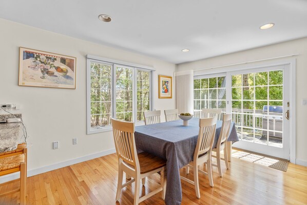 A dining area with a table set for four, large windows, and artwork on the walls.