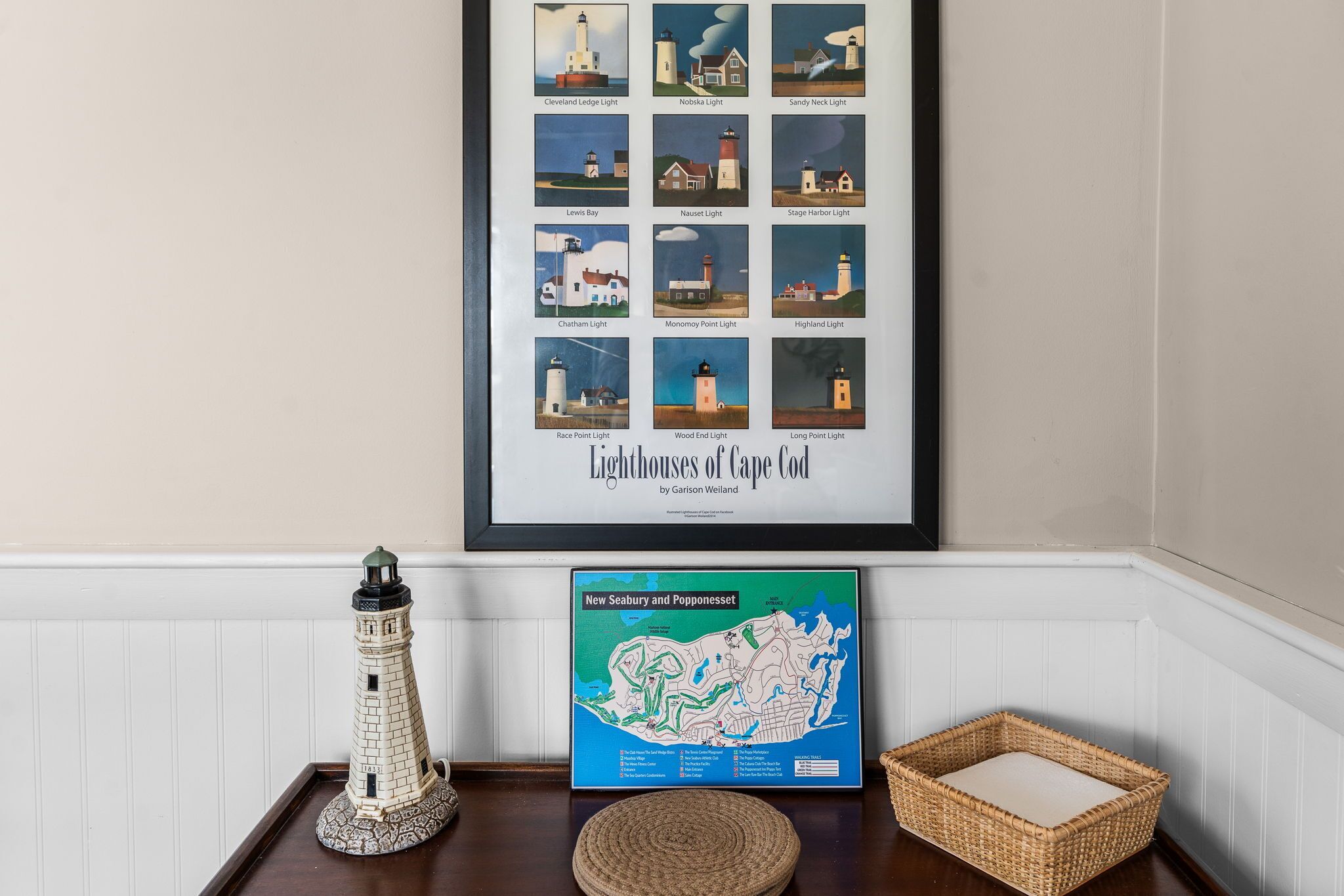 A framed map of Cape Cod lighthouses, a model lighthouse, and a map of New Seabury and Popponsett.