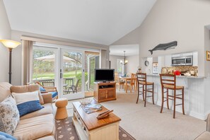 A living room with a TV, sofa, and dining area with chairs.