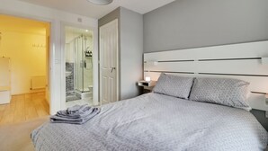 Ein Schlafzimmer mit einem Bett, einem Nachttisch mit Lampe, einem Kleiderschrank und einem Badezimmer mit Dusche.