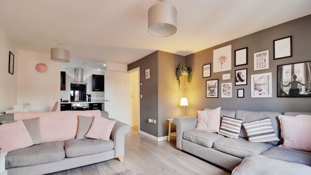 Ein modernes Wohnzimmer mit zwei grauen Sofas, einem Couchtisch, einem Teppich und einer Küche im Hintergrund.