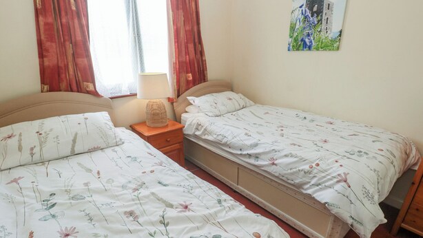Un dormitorio con dos camas, una mesita de noche, una lámpara y un cuadro colgado en la pared.