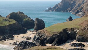 Un paisaje costero con acantilados rocosos, una playa arenosa y el océano.