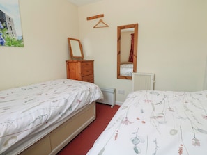 Un dormitorio con dos camas, un aparador, un radiador y un espejo.