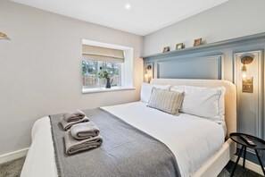 A bedroom with a bed, a window with a view, a bedside table, and a wall-mounted light fixture. - Corn Flour Lodge, Pitkerro Mill (Dundee)