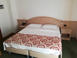 A double bed with a patterned bedspread, two bedside tables, and a wooden headboard.
