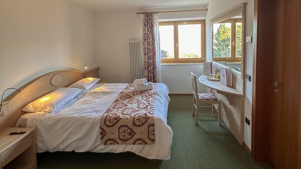 Un dormitorio con cama, mesita de noche, silla, ventana y puerta.