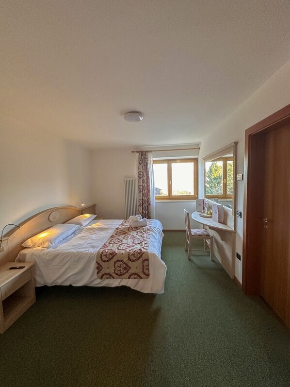 A bedroom with a bed, bedside table, chair, window, and a door. - Hotel Alpe Bellaria (Candriai)