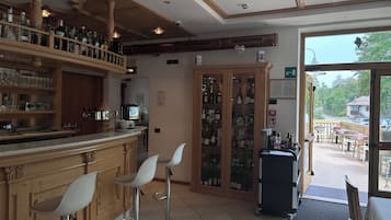 A bar area with stools, shelves of bottles, and a view of the outside.