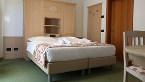 A bedroom with a bed, wooden wardrobe, and a chair. - Hotel Alpe Bellaria (Candriai)