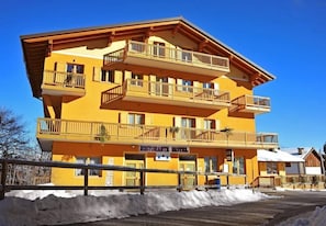 A multi-story hotel with balconies, a sign indicating it's a restaurant hotel, and a clear blue sky.