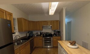 Eine Küche mit Holzausstattung, Edelstahlgeräten, einem Kühlschrank, Backofen und einer Kaffeemaschine.