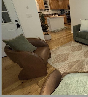 Ein Wohnzimmer mit einem braunen Ledersessel, einem gemusterten Teppich und einem grauen Sofa.