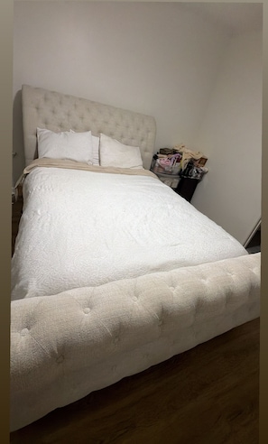 Ein ordentlich bezogenes Bett mit einer gebügelten Kopfstütze, einer weißen Daunendecke und mehreren Kissen.