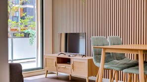 A modern living room with a TV, wooden furniture, and a large window.