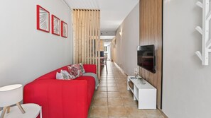Ein modernes Wohnzimmer mit einem roten Sofa, einem an der Wand befestigten Fernseher und einer Holzwand.
