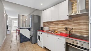 Eine moderne Küche mit roter Arbeitsplatte, Edelstahlgeräten und einer strukturierten Spritzschutzwand.