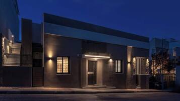 Un bâtiment moderne à la façade sombre, doté d’une entrée illuminée et d’une plaque signalétique bien visible.