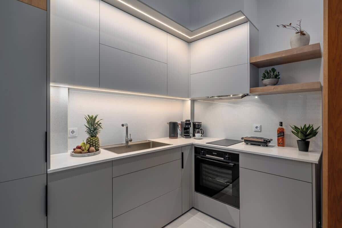 Una cucina moderna con mobili grigi, lavastoviglie, macchina da caffè e una ciotola di frutta.