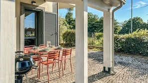 Eine Terrasse im Freien mit Esstisch, Grill und überdachter Sitzgruppe.