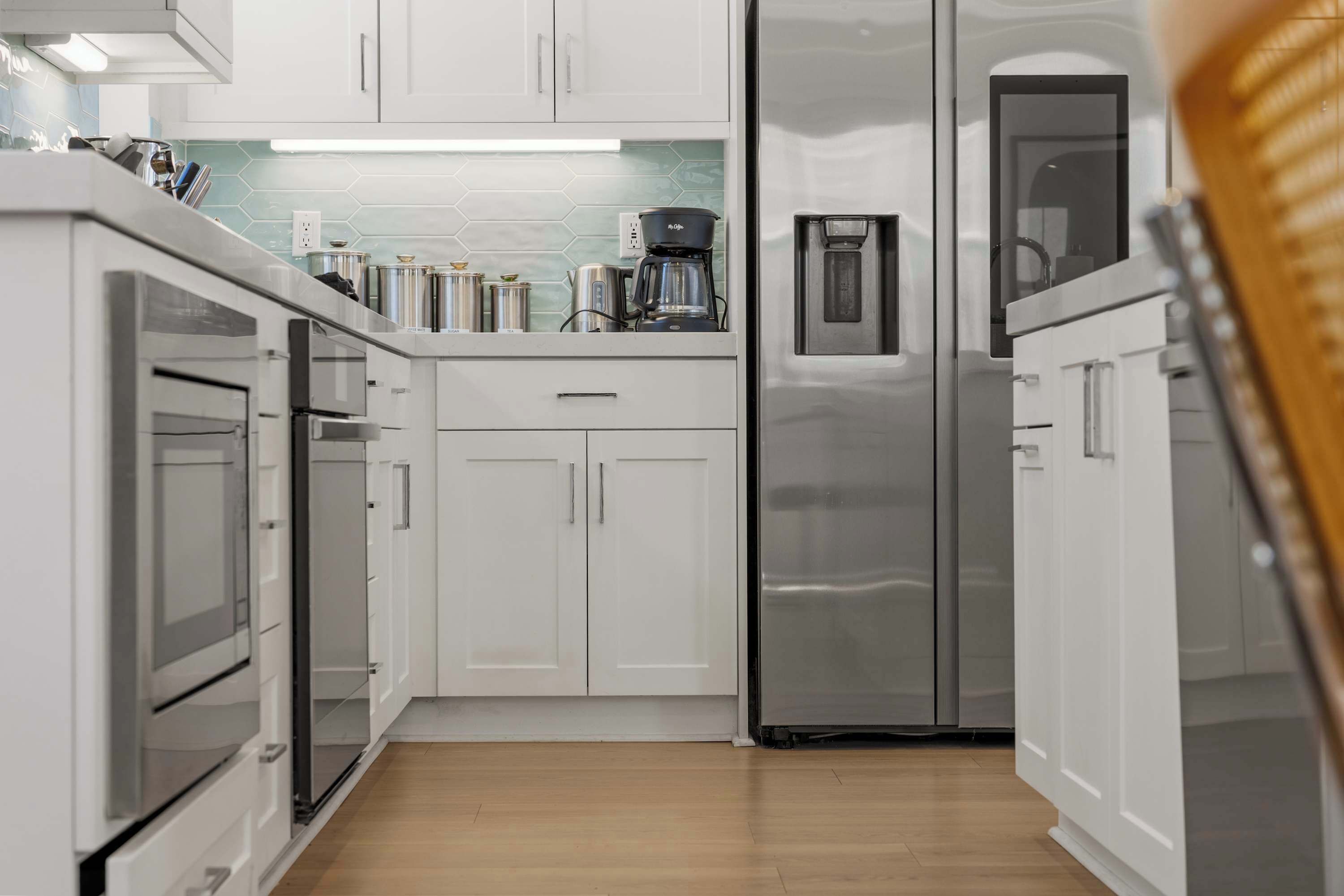 A modern kitchen with white cabinets, stainless steel appliances, and a coffee maker on the countertop.
