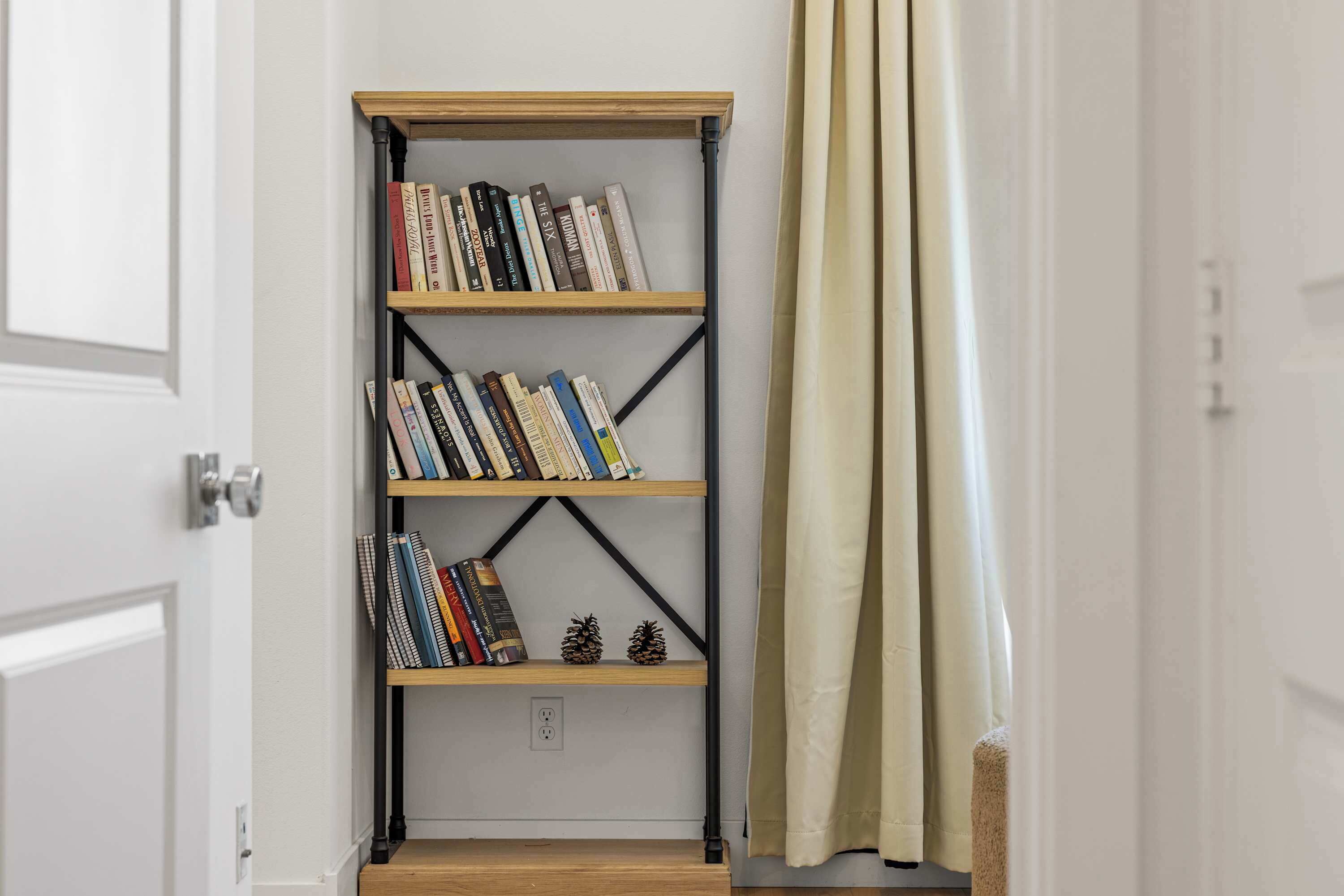 A bookshelf with multiple shelves, a door with a handle, and a curtain.