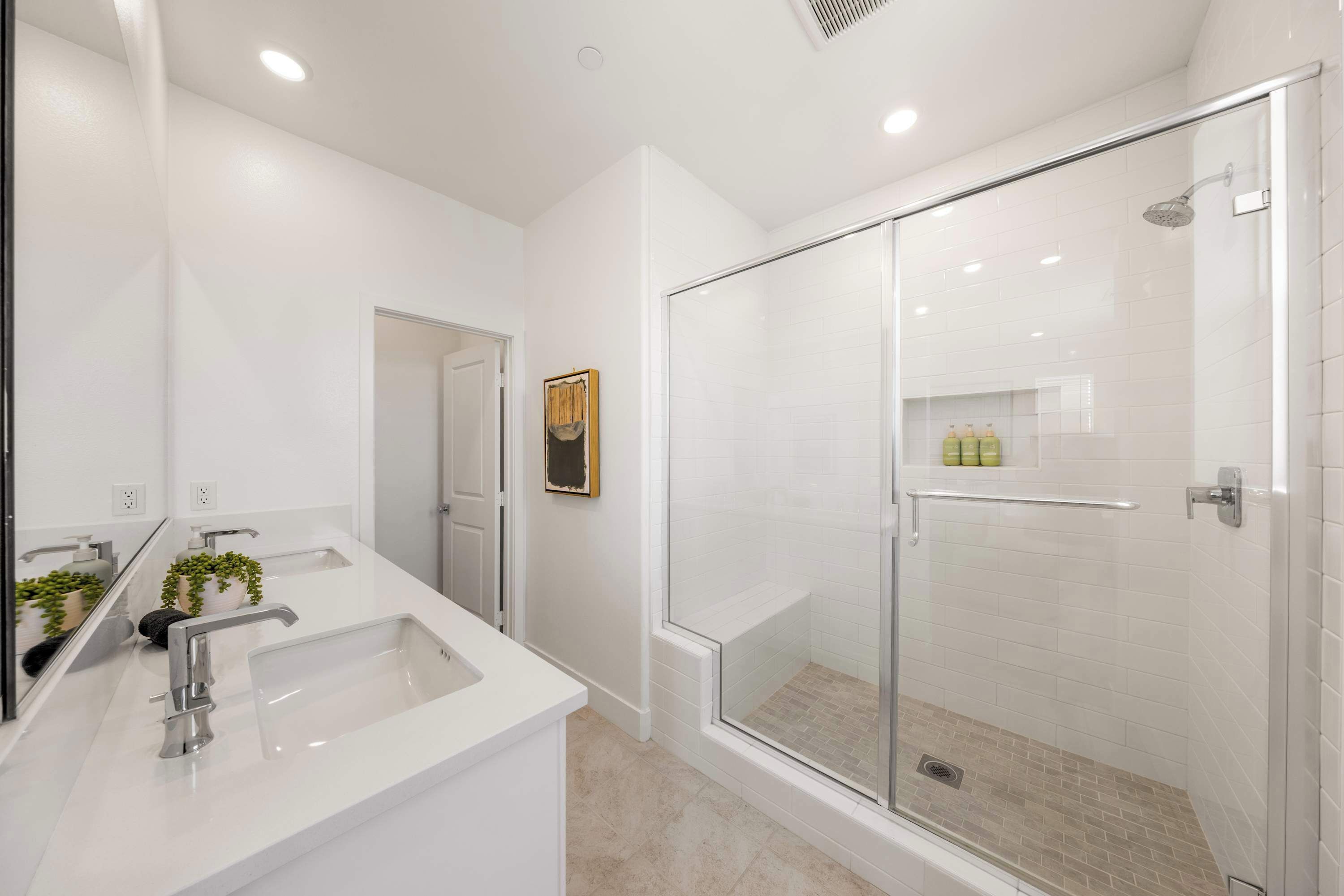 A modern bathroom with a glass shower enclosure, a white sink, and a mirror.