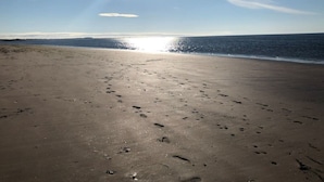 Une plage parsemée d’empreintes, un ciel dégagé et un soleil éclatant.