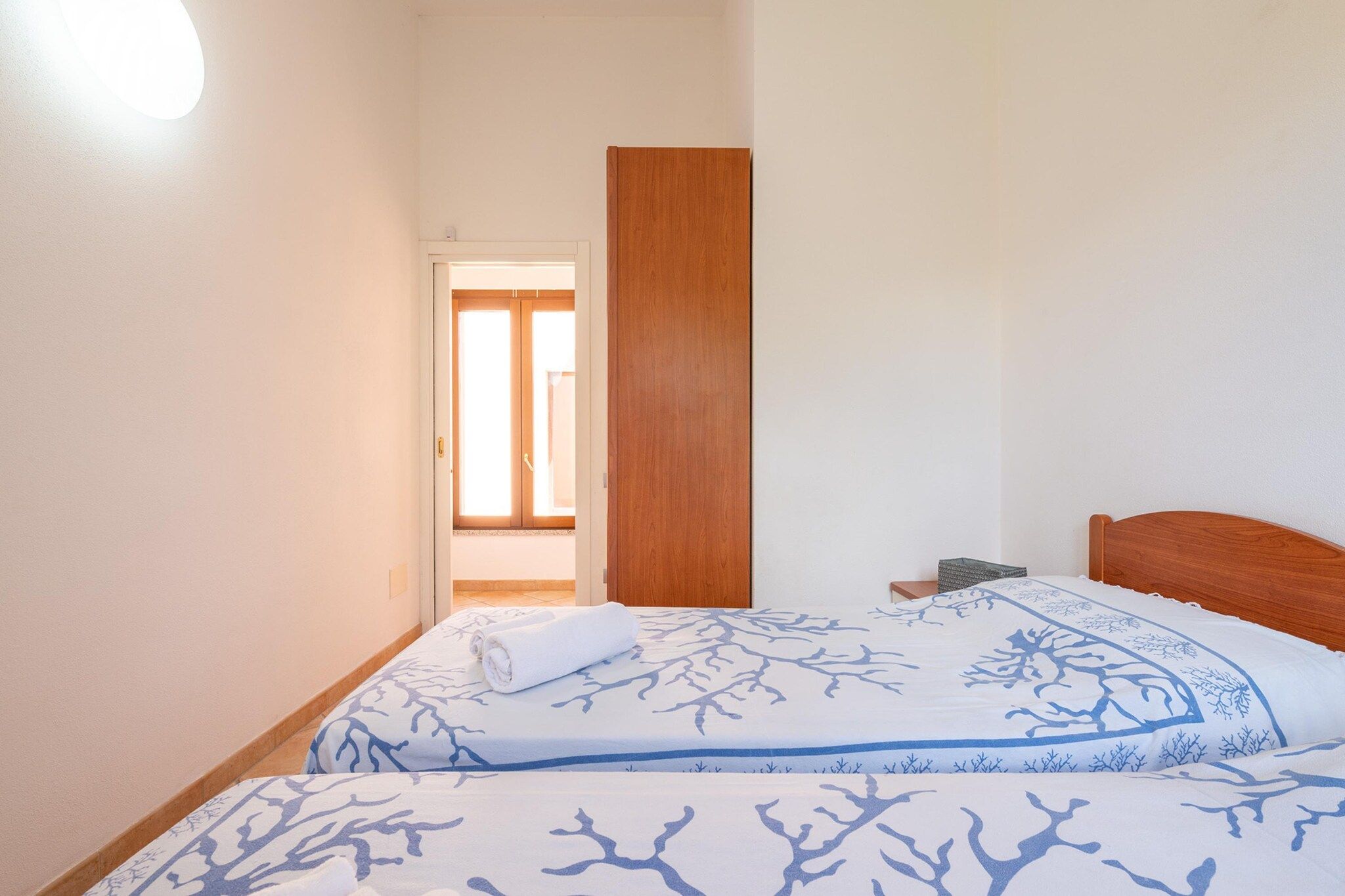 Ein Schlafzimmer mit einem Bett, einer Holztür und Blick auf einen Flur.