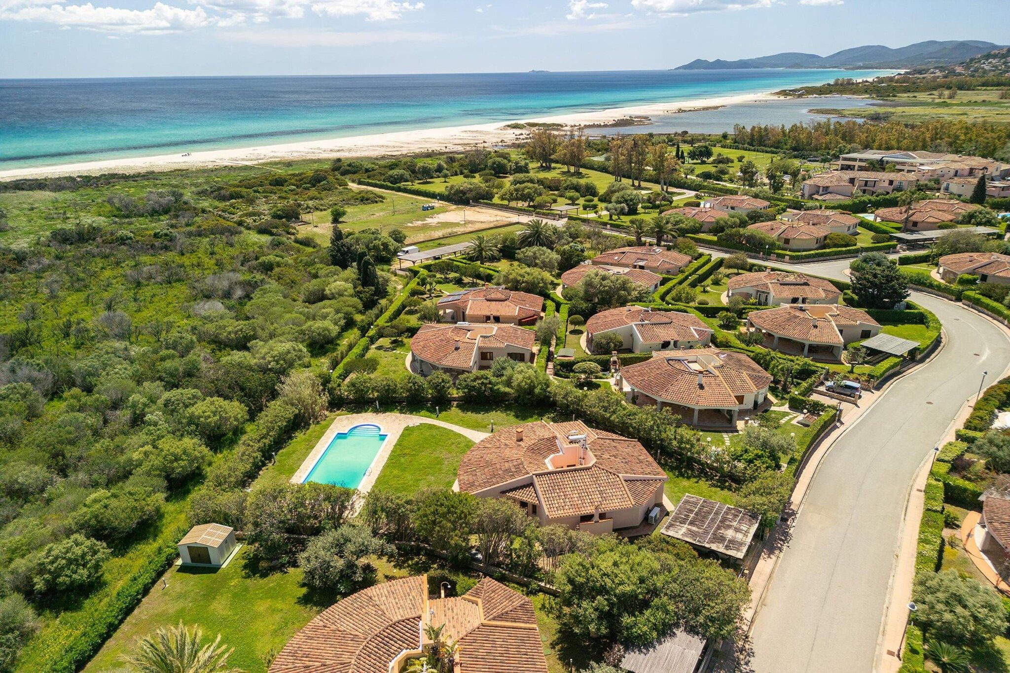 Un quartiere residenziale con case, una piscina e una spiaggia sullo sfondo.
